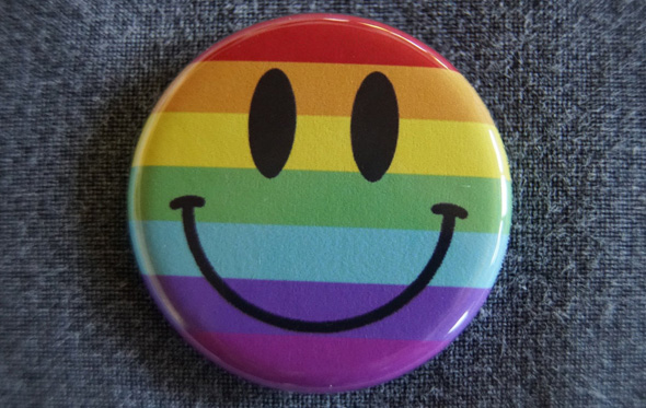 Ansteck-Button mit Smiley vor Regenbogenfarben