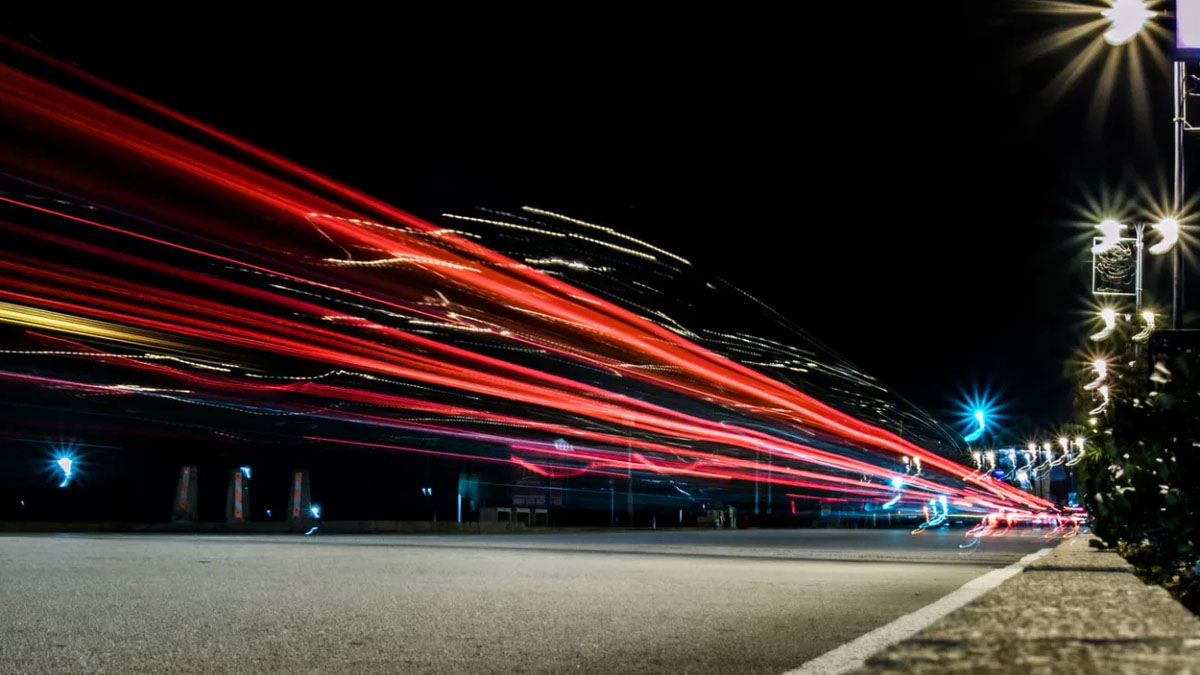 Nächtliche Straße mit Lichtspuren vorbeifahrender Autos