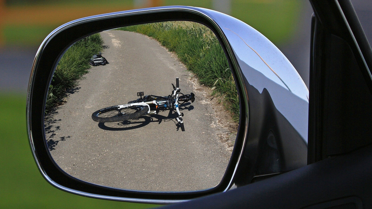 Rückspiegel eines Autos, in dem ein gestürztes Fahrrad zu sehen ist