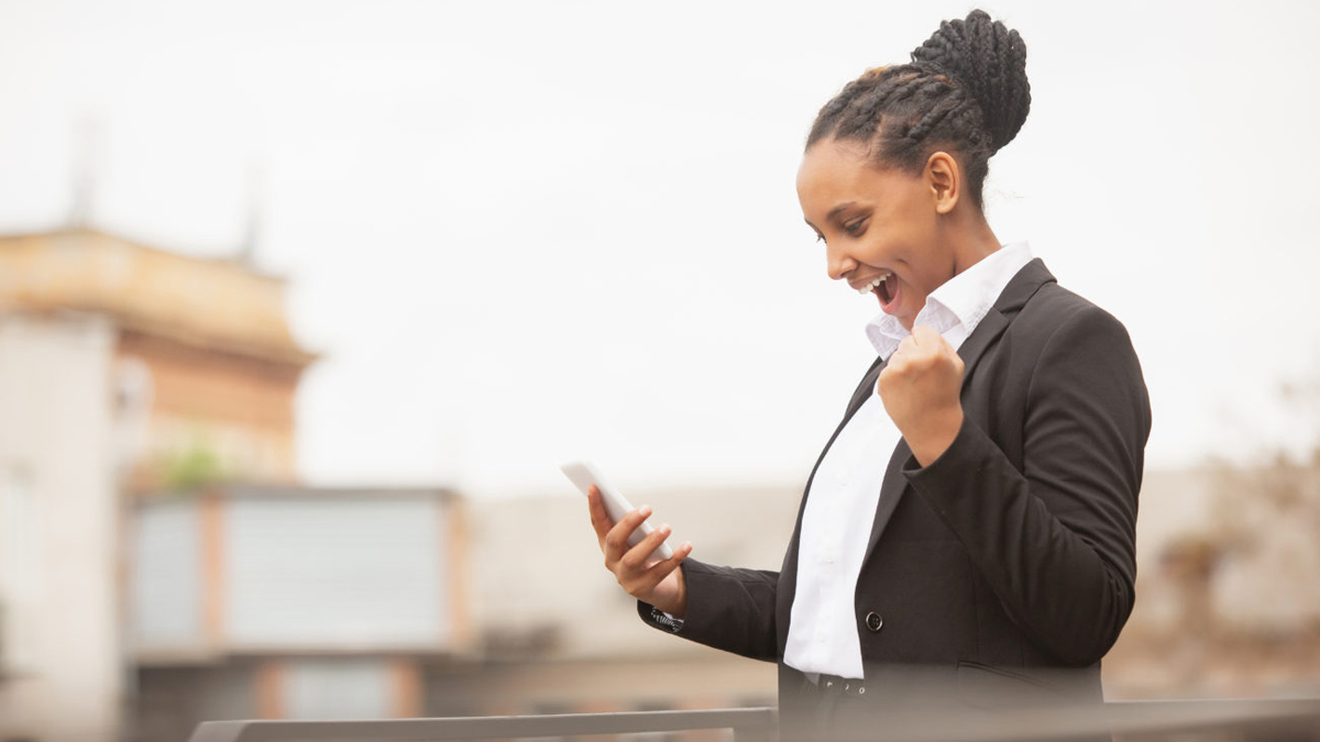 Geschäftsfrau hält Smartphone und freut sich über eine Nachricht