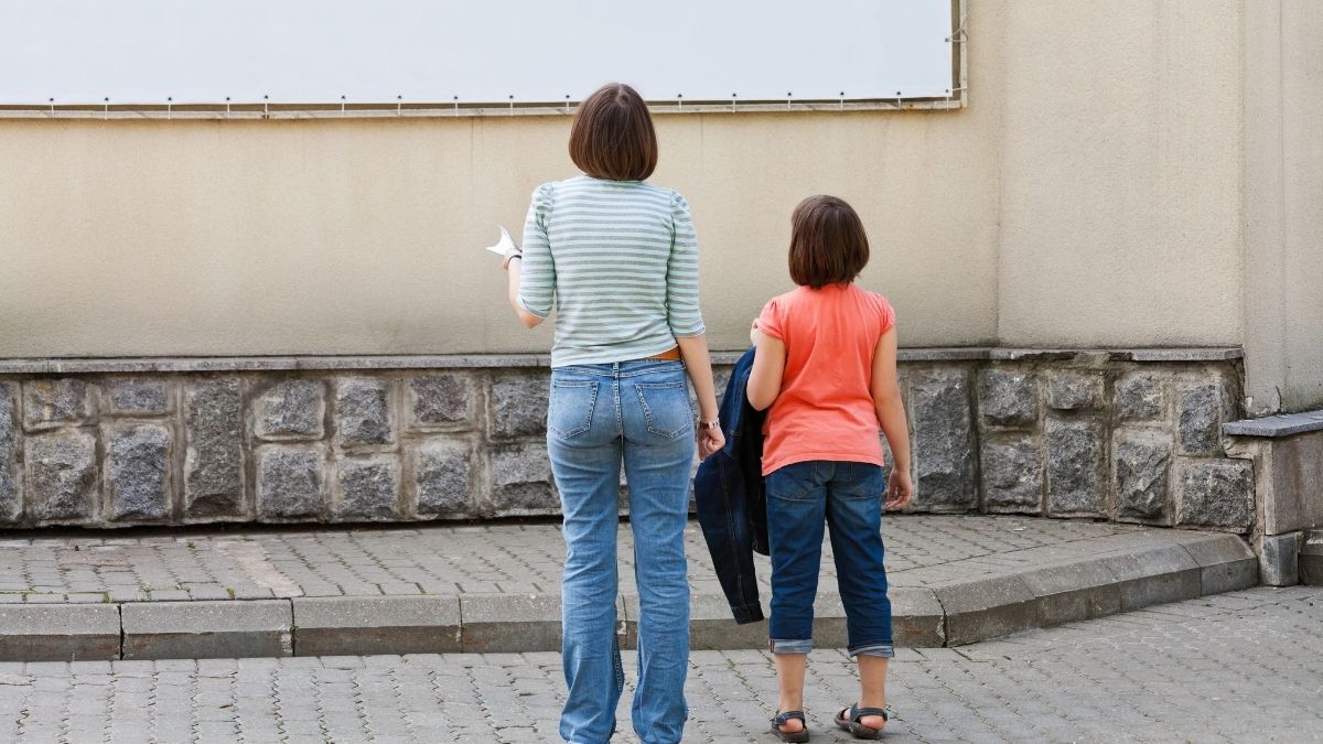 Frau und Mädchen vor einer Werbetafel an Hauswand