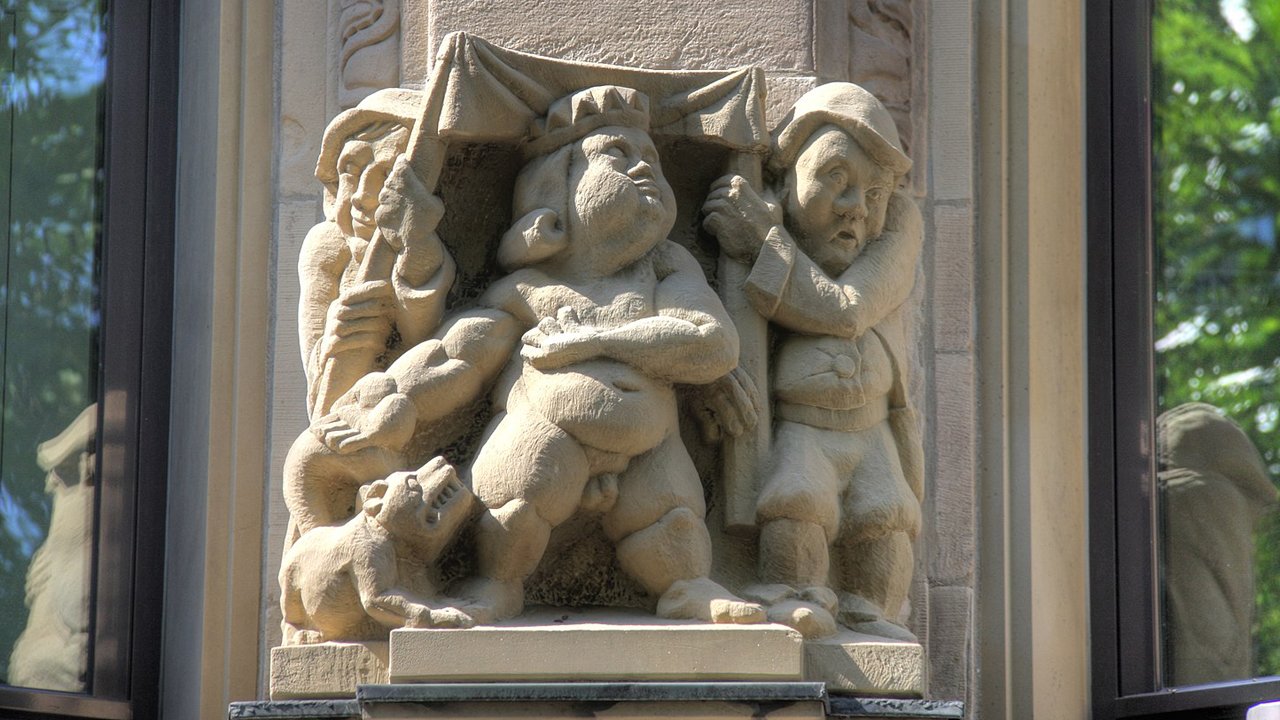 Skulptur an einem Kölner Bürohaus, die eine Szene aus dem Märchen 'Des Kaisers neue Kleider' darstellt.