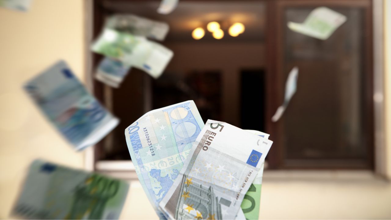 Euro-Scheine fliegen aus einem offenen Fenster heraus.