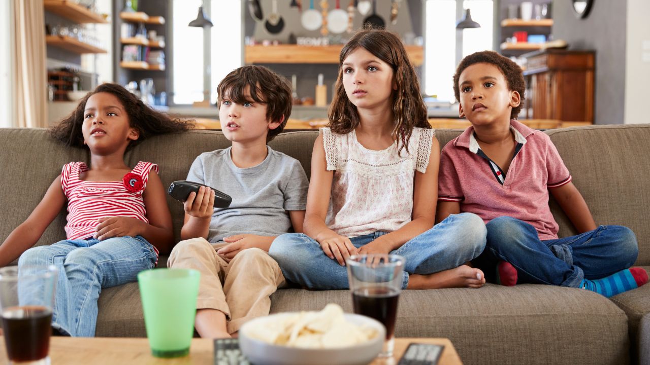 Vier Kinder auf einer Couch beim Fernsehen.