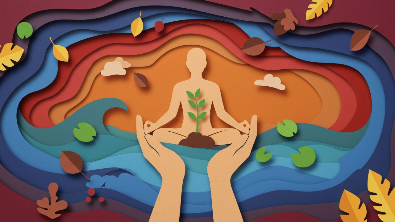 Illustration im Papierschnitt-Stil: Eine beigefarbene Silhouette meditiert im Lotussitz, wobei ein kleiner grüner Pflanzensetzling aus ihrer Mitte wächst. Zwei große Hände tragen die Figur schützend von unten. Der Hintergrund besteht aus geschichteten, wellenförmigen Papierlagen, die unten blaues Wasser mit Seerosen und oben einen warmen, orange-roten Himmel mit Wolken und herbstlichen Blättern darstellen.