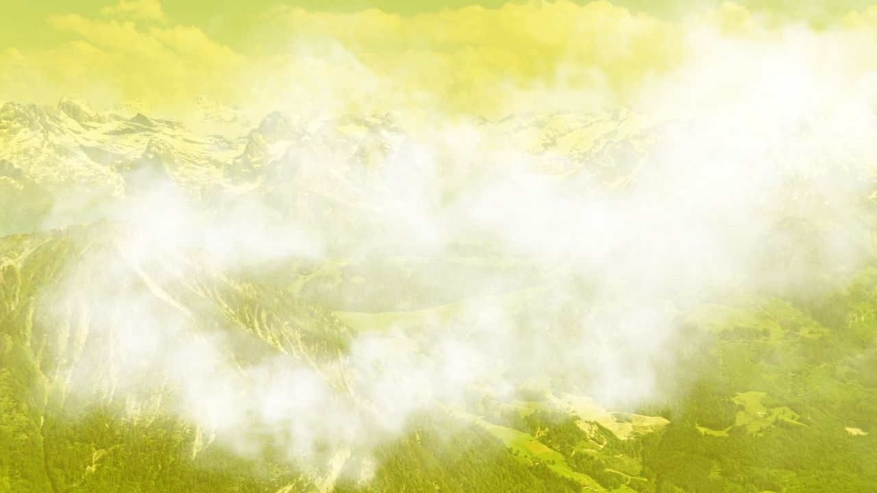 Weißer Rauch vor gelb gefärbtem Alpenpanorama im Hintergrund.