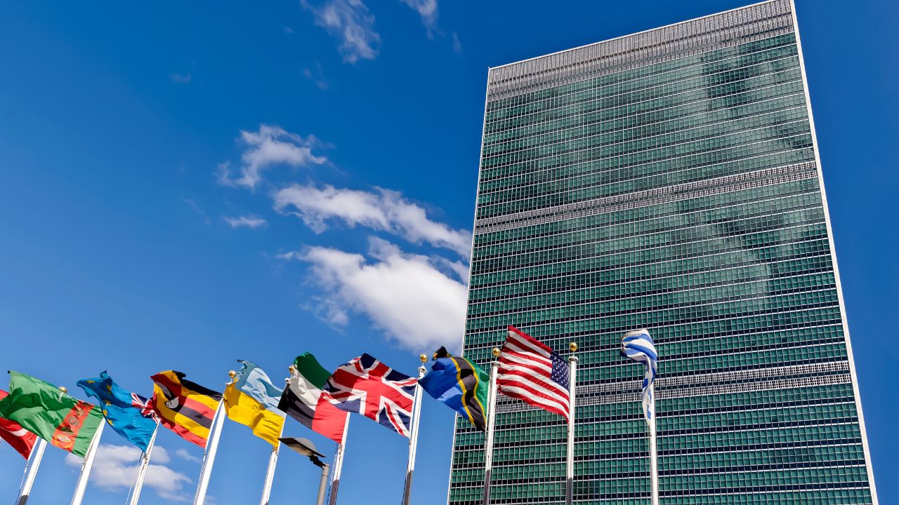 Sitz der Vereinten Nationen in New York mit einer Reihe Flaggen davor.