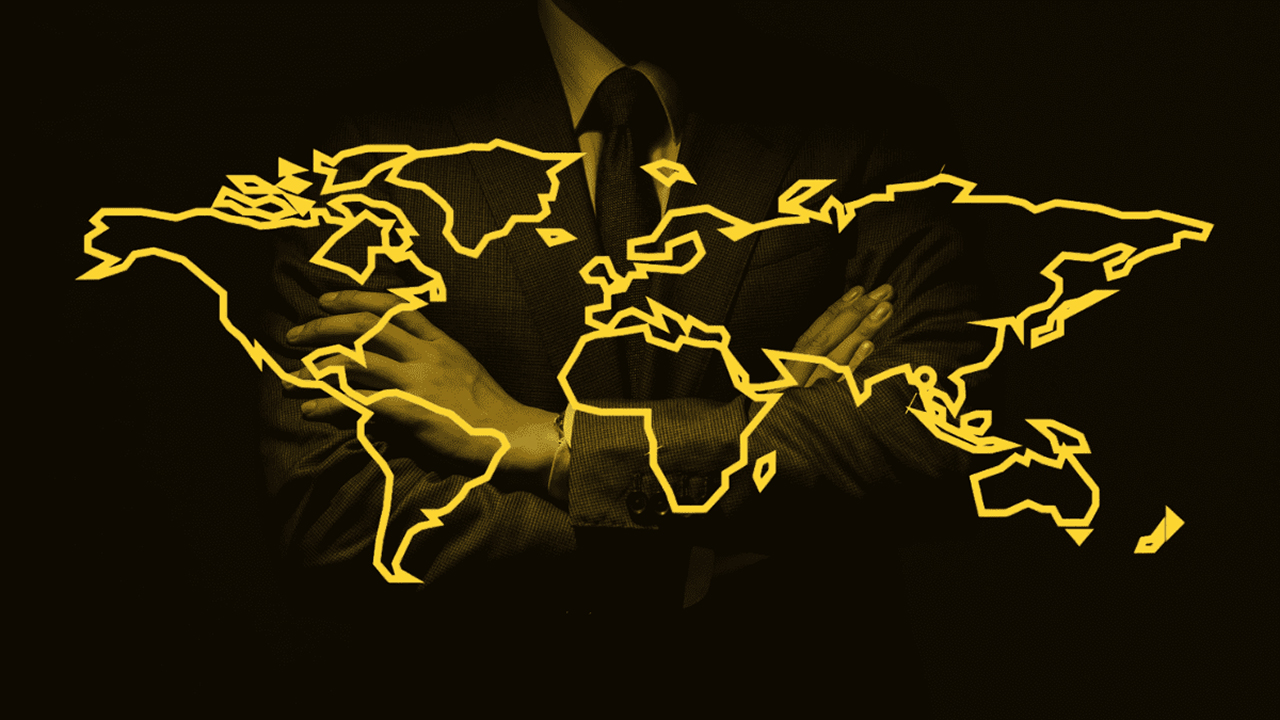 Symbolbild für globale Macht: Ein Mann im Anzug steht mit verschränkten Armen hinter einer stilisierten, gelben Kontur der Weltkarte.