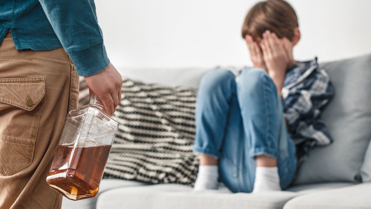 Gestresster Junge mit seinem alkoholkranken Elternteil.