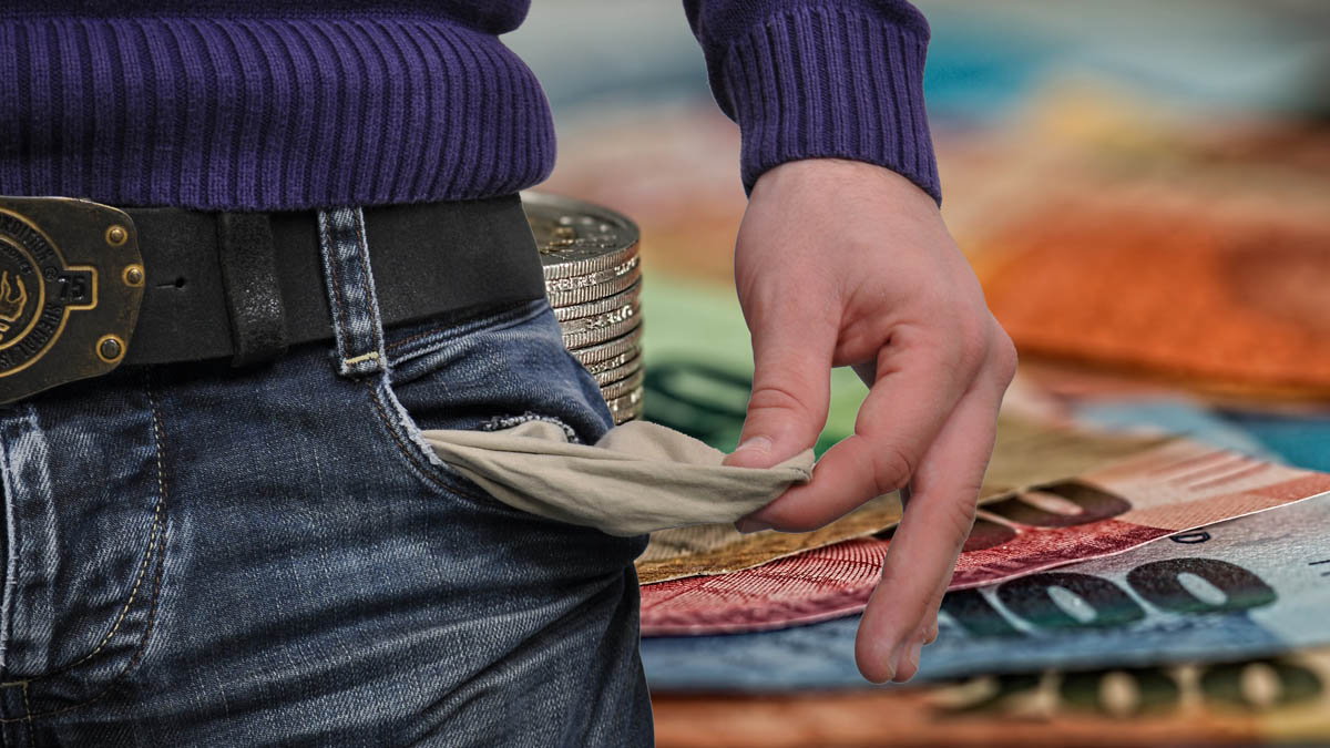 Mann zieht Inneres seiner Hosentasche hervor;im Hintergrund Banknoten und Münzen