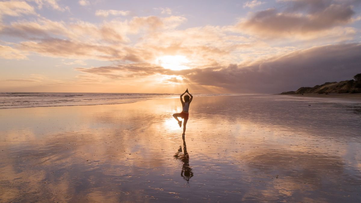 Mann macht Yoga-Übung am Strand in der Abenddämmerung