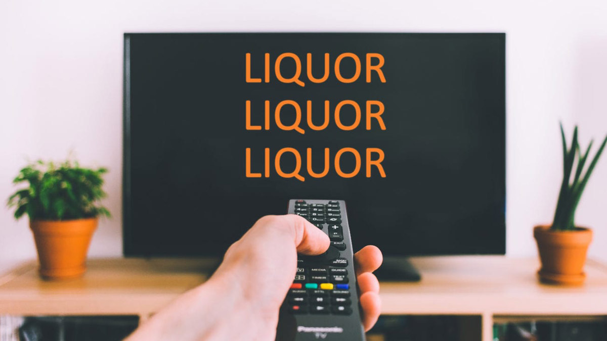 Fernsehbildschirm mit Aufrschrift 'liquor' (Spirituosen), davor eine Hand mit Fernbedienung